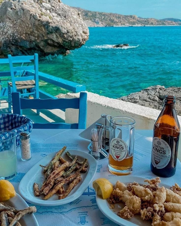 This may contain: a table topped with plates of food next to a bottle of beer and some water