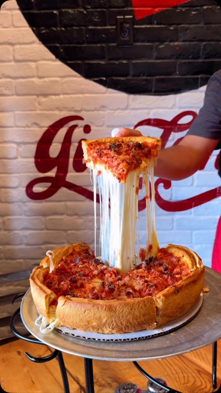 This may contain: a deep dish pizza being served on a silver platter