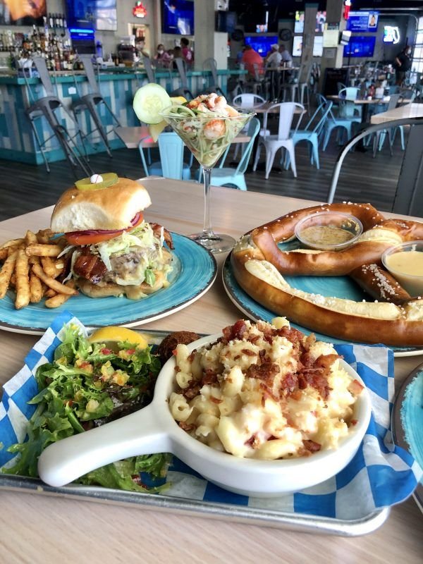 This may contain: a table topped with blue plates filled with food next to glasses of beer and pretzels
