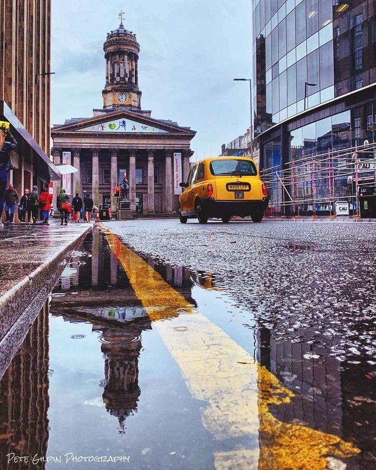 This may contain: a yellow taxi cab driving down a street next to tall buildings