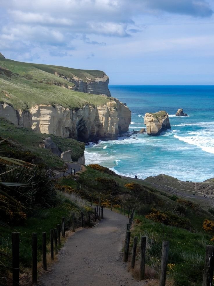 This may contain: a path leading to the ocean with cliffs in the background