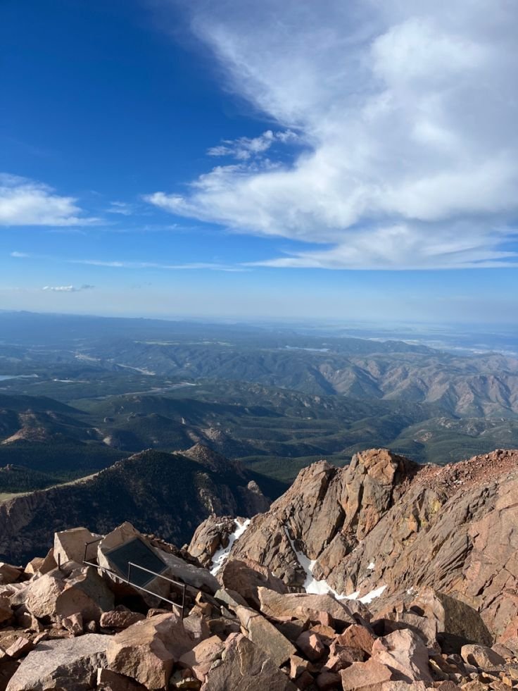 This may contain: a view from the top of a mountain looking down at some rocks and mountains in the distance