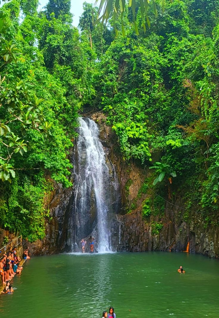 This may contain: people are swimming in the water near a waterfall