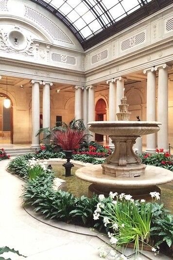 This may contain: the inside of a building with a fountain and flowers