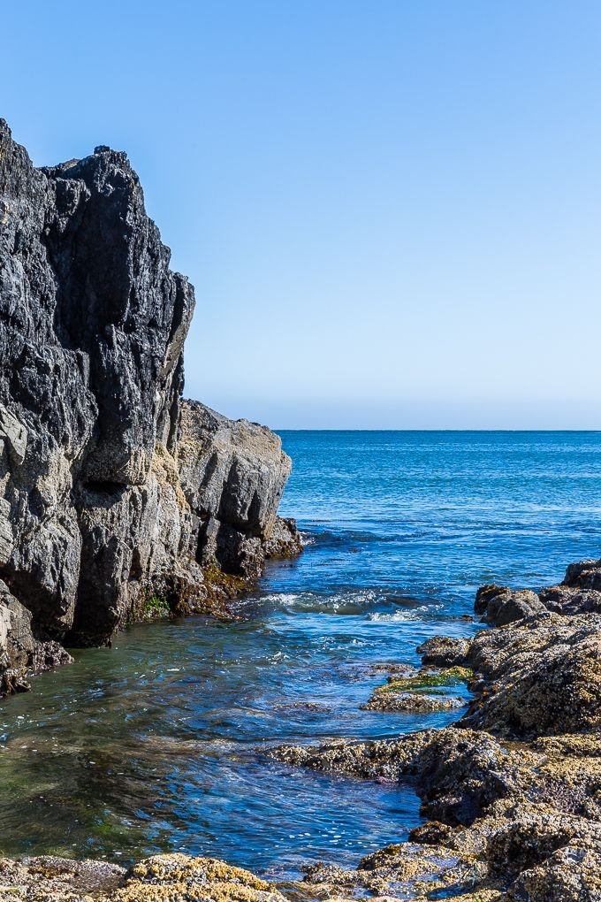 This may contain: there is a rock outcropping next to the ocean with water running through it