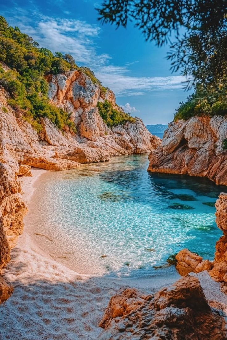 This may contain: the beach is surrounded by rocks and water