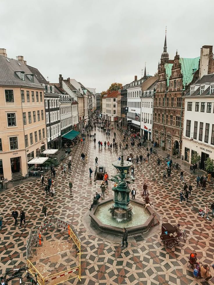 This may contain: an aerial view of people walking around in a city square with a fountain and clock tower