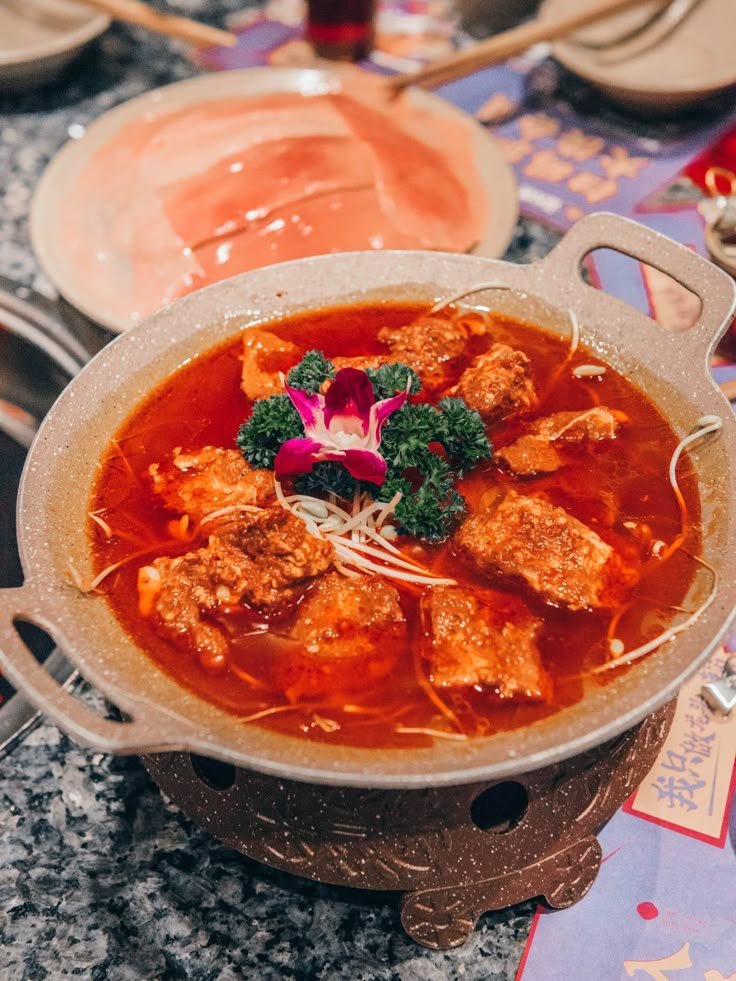 This may contain: a bowl of soup with meat and broccoli in it sitting on a table