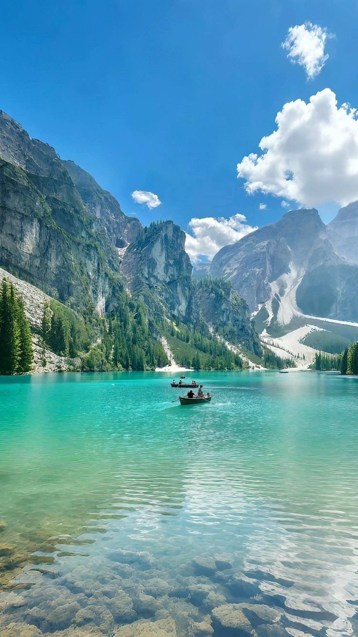 This may contain: two boats floating on top of a lake surrounded by mountains