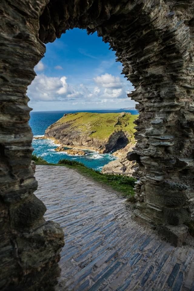 This may contain: an archway leading to the ocean through stone walls