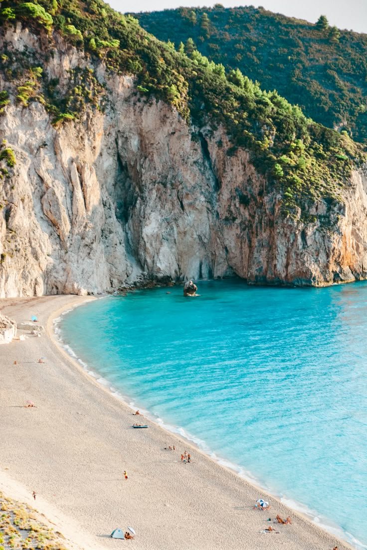 This may contain: the beach is clear and blue with people on it