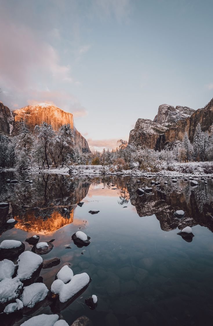 This may contain: a lake surrounded by snow covered rocks and mountains