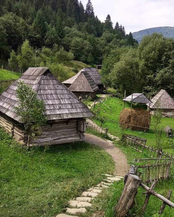 This may contain: an old village in the mountains with grass and straw huts
