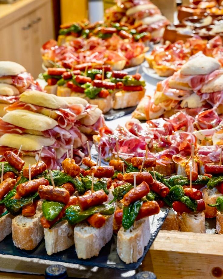 This may contain: many different types of appetizers on display in a buffet style setting, including breads and sandwiches