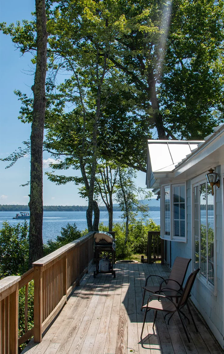 This may contain: a deck with chairs on it next to trees and water