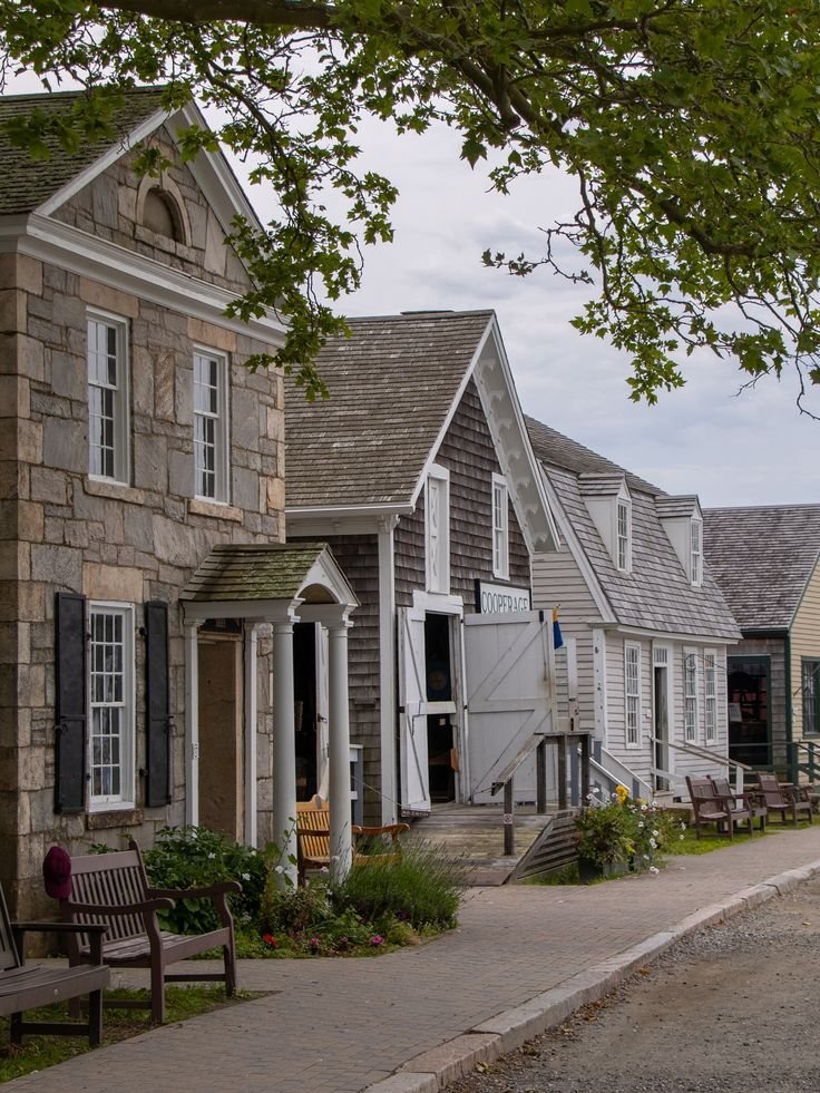 This may contain: a row of houses on the side of a road next to a tree and sidewalk