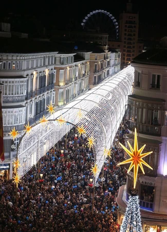 This may contain: a large group of people standing around a christmas tree in the middle of a city
