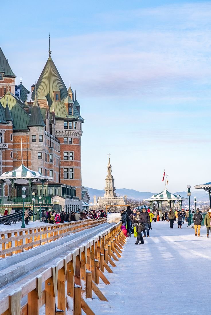 This may contain: people are walking on the boardwalk in front of some large buildings with towers and spires