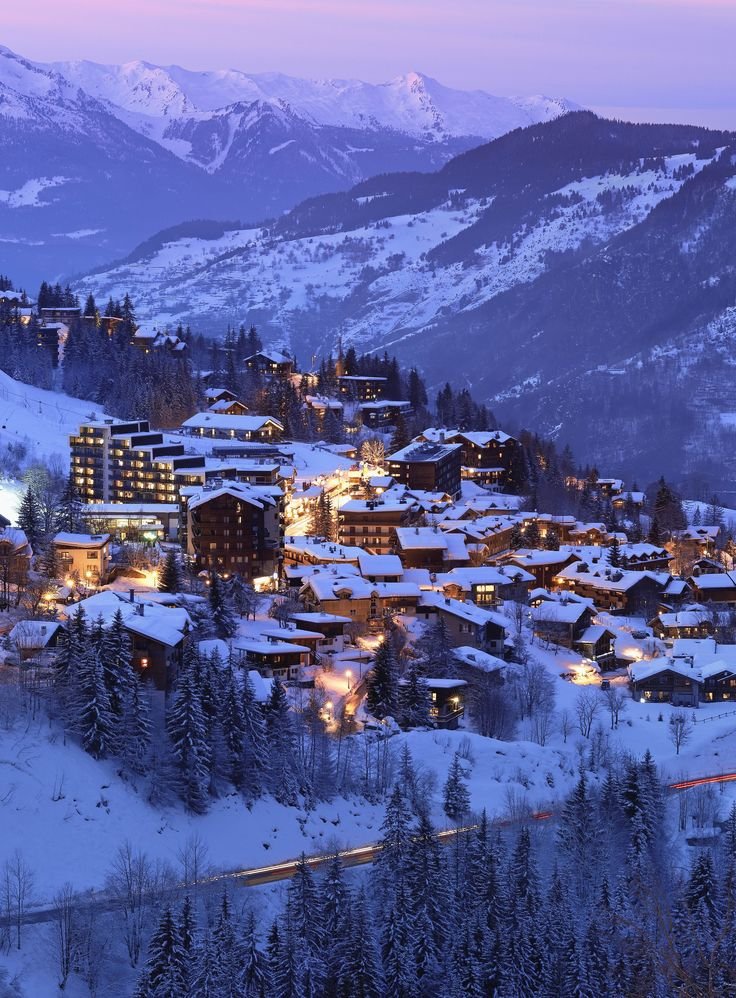 This may contain: a snowy mountain town lit up at night
