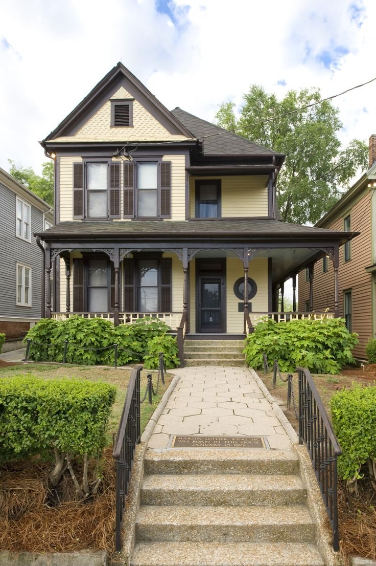 This may contain: a house with steps leading up to the front door and bushes in front of it