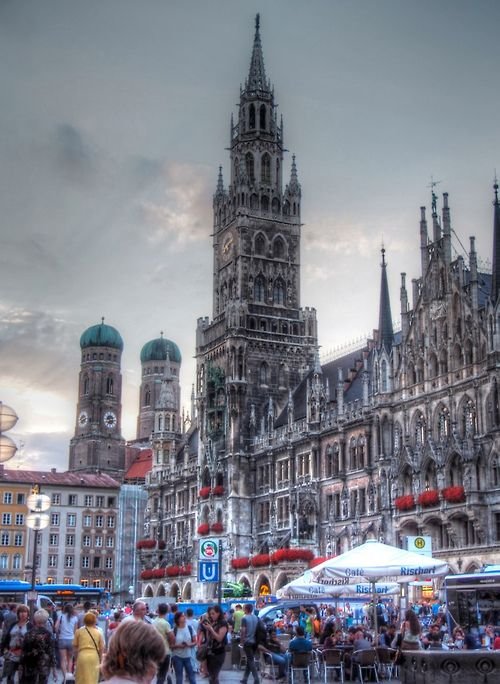 This may contain: people are walking around in front of an old building with many spires and towers