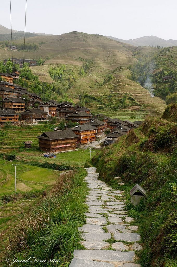 This may contain: a stone path leading to some houses in the mountains