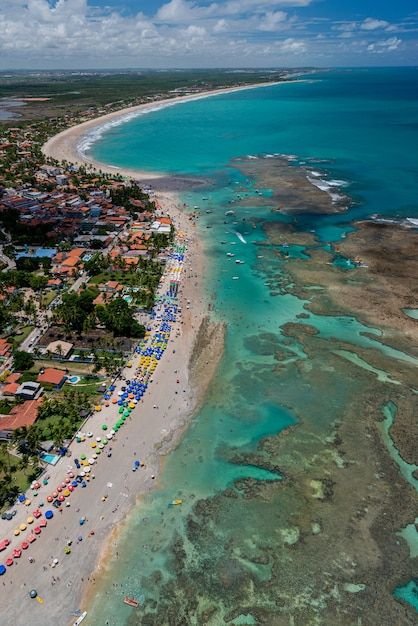 This may contain: an aerial view of a beach and ocean with people on the sand, surrounded by blue water