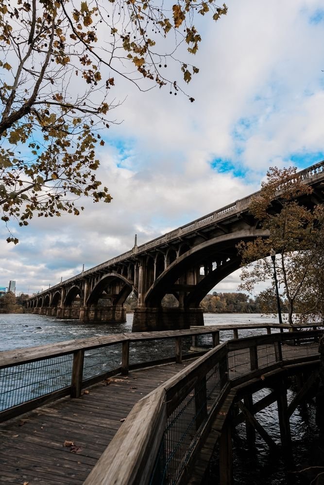 This may contain: an old bridge over the water on a cloudy day