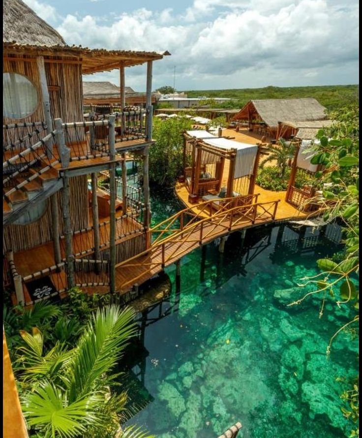 This may contain: the water is clear and blue in this tropical resort with wooden houses on stilts