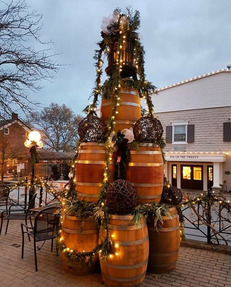 This may contain: a christmas tree made out of wine barrels with lights on it's sides and wreaths around the top