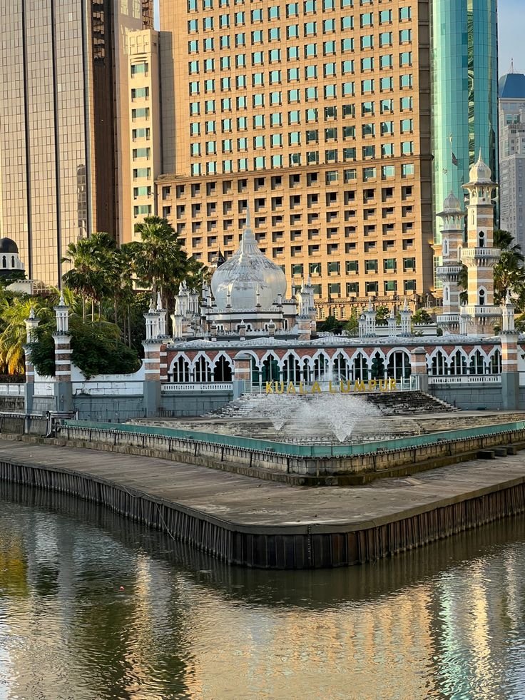 This may contain: a fountain in the middle of a body of water surrounded by tall buildings