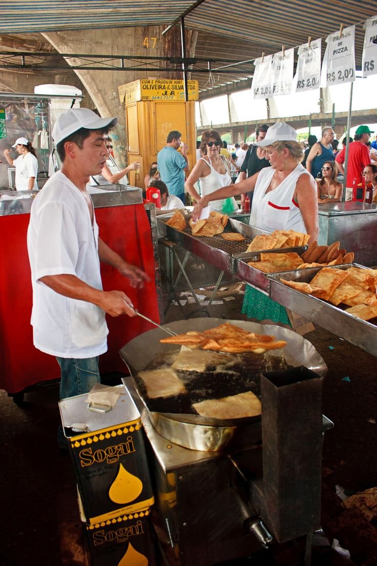 This may contain: a man cooking food on top of a grill in front of a group of people