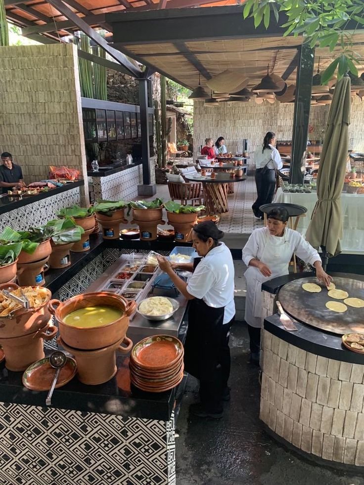 This may contain: people are preparing food at an outdoor restaurant