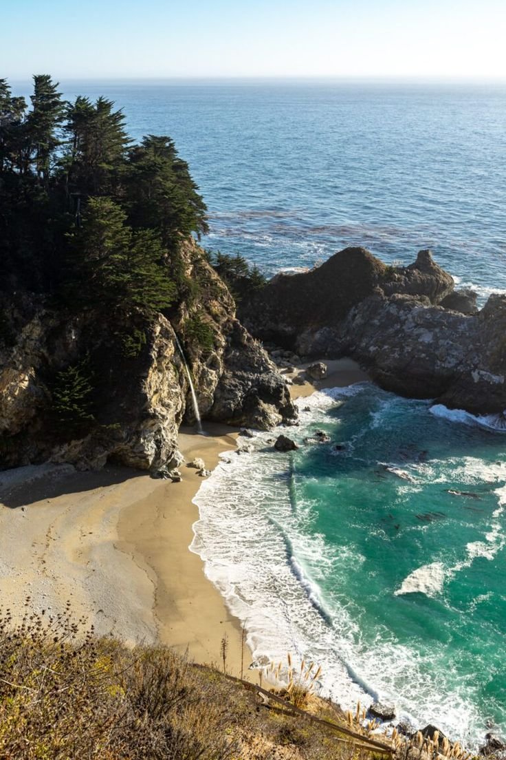 This may contain: the beach is next to some trees and water