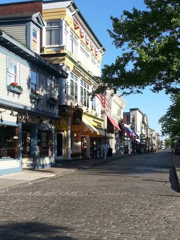 This may contain: an empty street lined with shops on both sides and trees in the middle of it