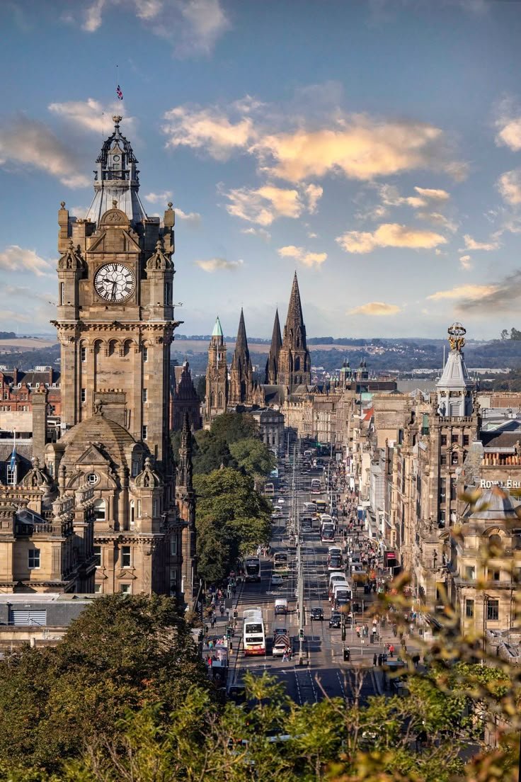 This may contain: a large clock tower towering over a city with tall buildings on both sides and trees in the foreground