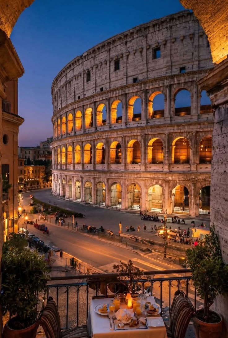 This may contain: the roman colossion is lit up at night, with tables and chairs outside