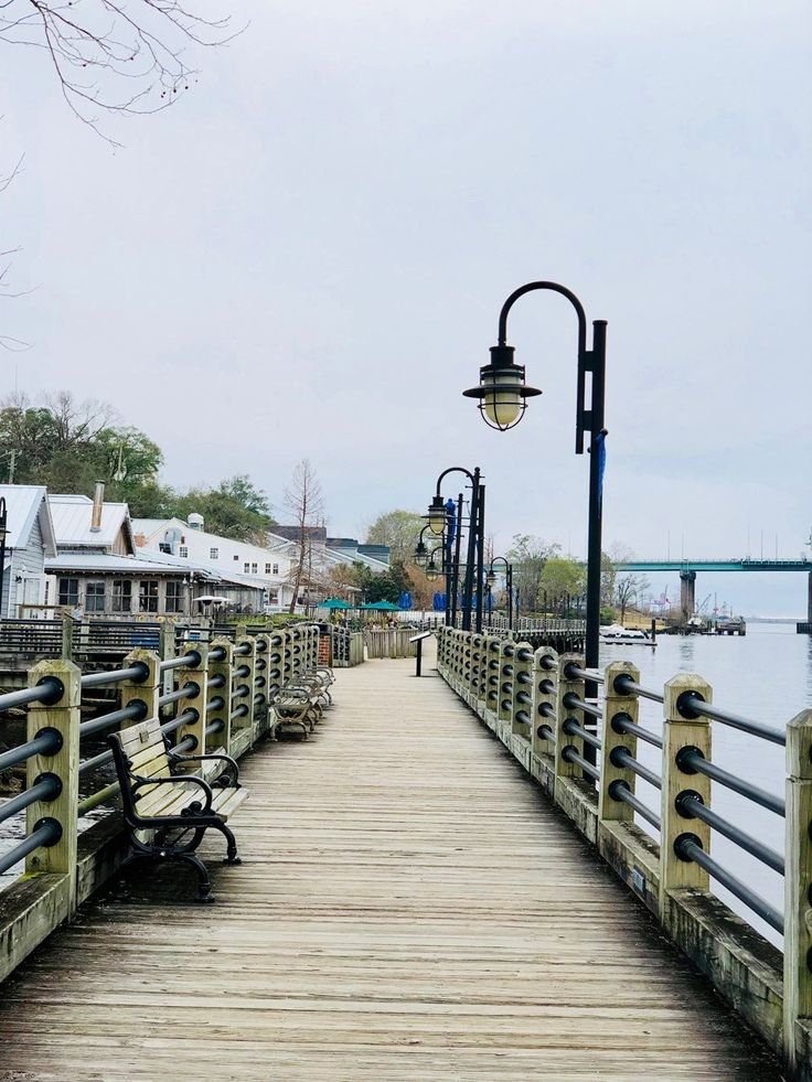 This may contain: a wooden pier with benches next to it and a street light on the side walk