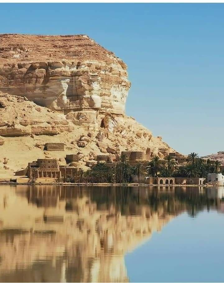 This may contain: an image of a lake in the middle of desert with mountains and buildings around it