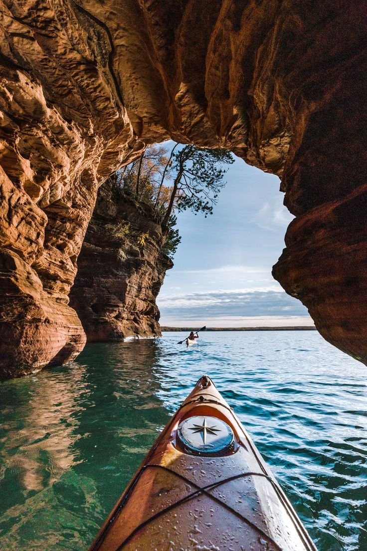 This may contain: a kayak is in the water near some cliffs