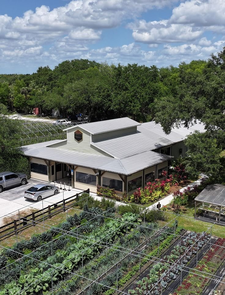 This may contain: an aerial view of a building with many plants growing in the yard and parking lot