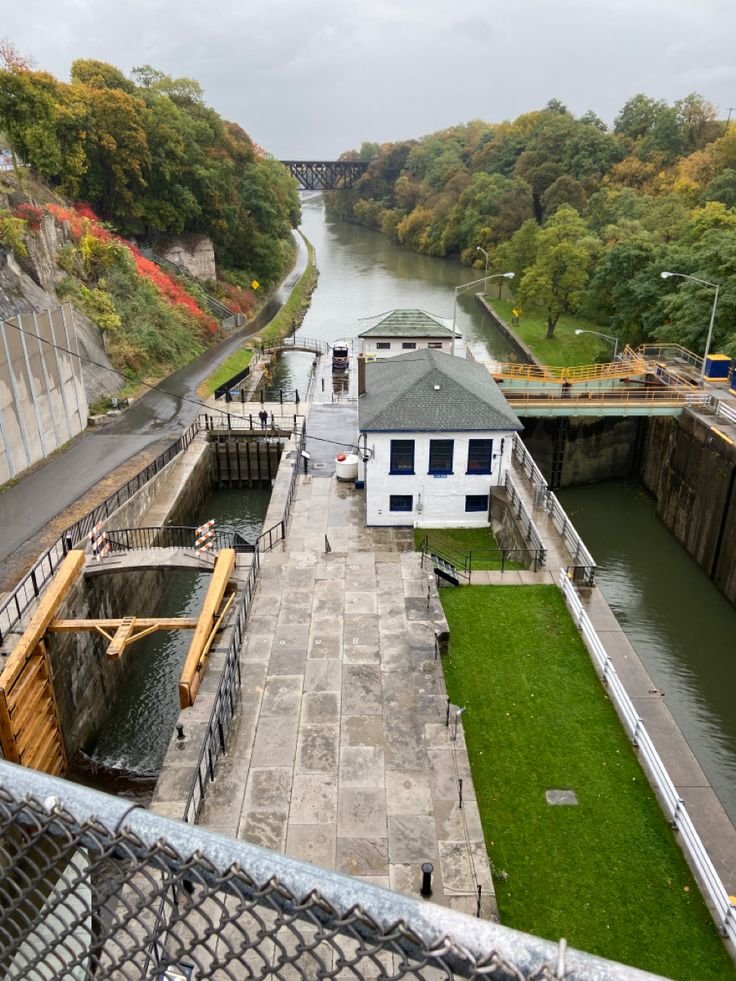 This may contain: an aerial view of a lock on a river with green grass and trees in the background