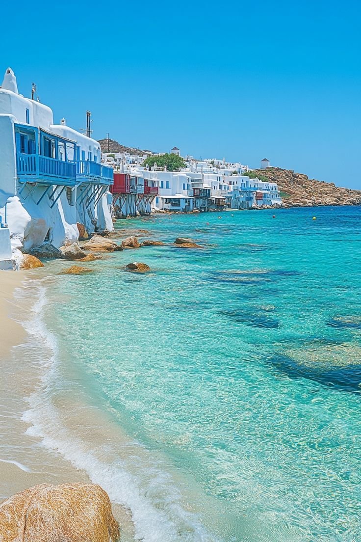 This may contain: the water is crystal blue and clear, with white buildings on either side that line the beach