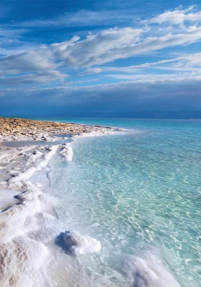 This may contain: the beach is covered in white sand and blue water with waves coming up on it