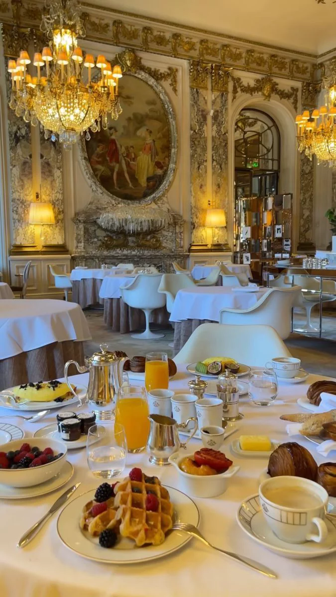 This may contain: a table set up with breakfast food and drinks for two people in a fancy dining room