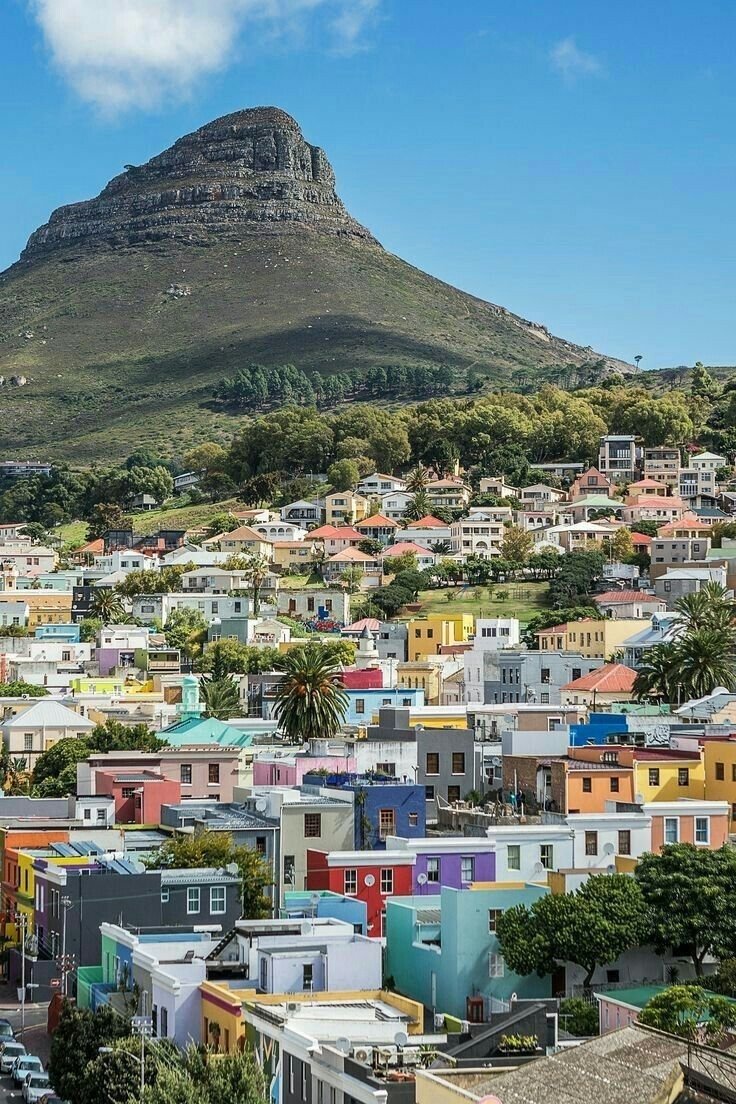 This may contain: the city has many colorful houses on it's sides and there is a mountain in the background