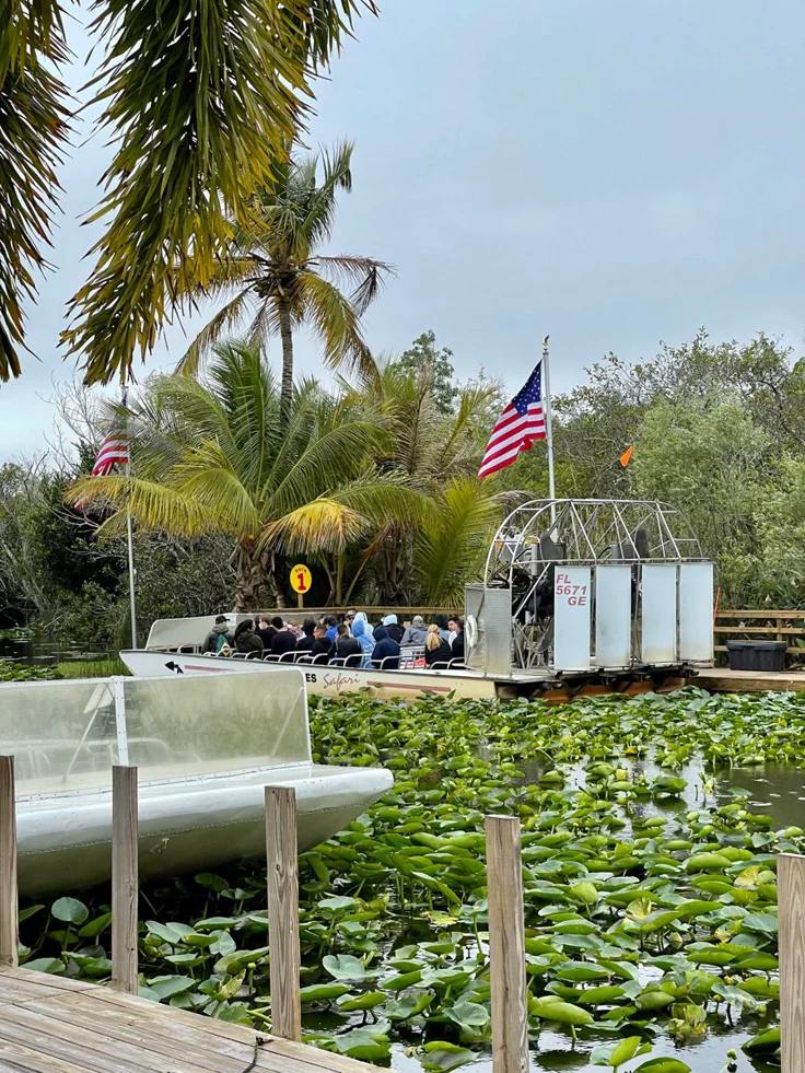 This may contain: there is a boat in the water with lily pads on it and people walking around