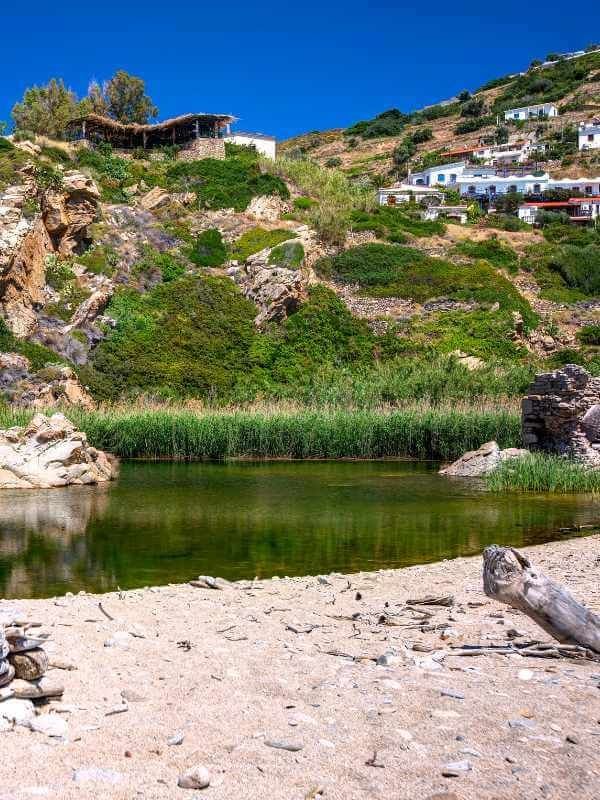 This may contain: there is a small body of water in the middle of a rocky area with houses on it