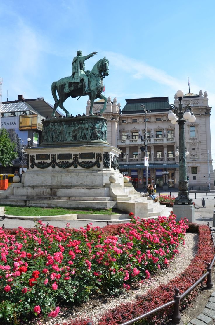 This may contain: a statue of a man on a horse in the middle of a flower garden