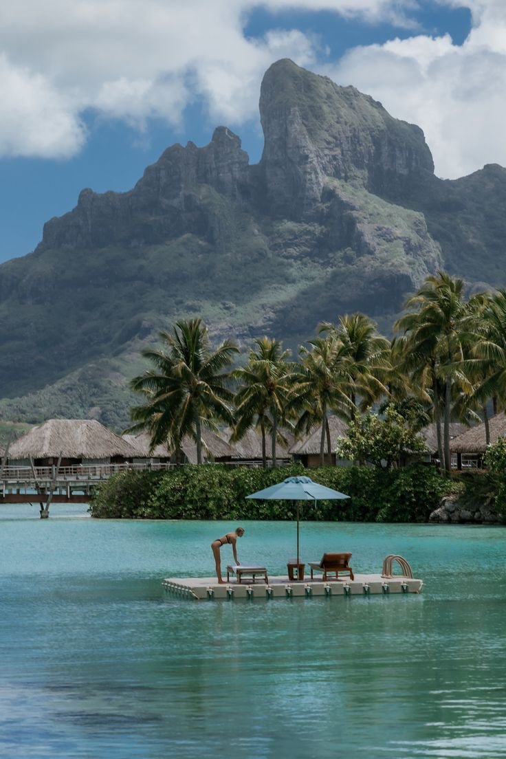 This may contain: the mountains are in the background and there is a pool with two chairs on it